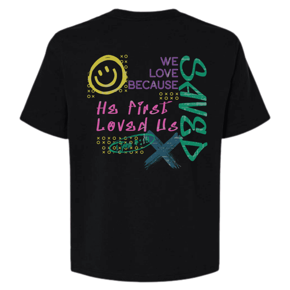 Back of black cropped tee with colorful graphic design featuring 1 John 4:19 and Christian message.