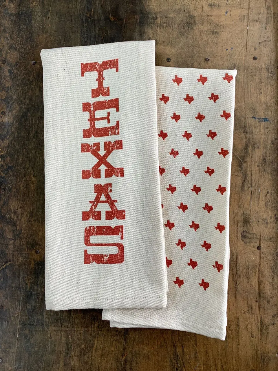 Folded Texas kitchen towel with vertical orange TEXAS print and orange state shapes