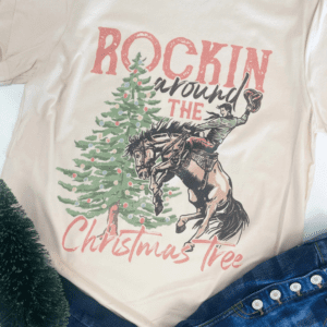 Flat lay of the “Rockin' Around The Christmas Tree” t-shirt showing the detailed western cowboy and Christmas tree design.