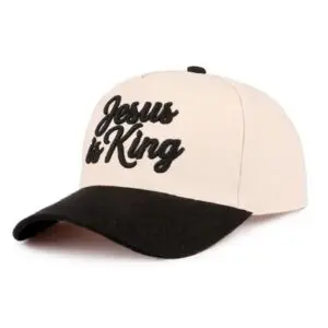 Cream and black baseball cap featuring raised black embroidered "Jesus is King" lettering.