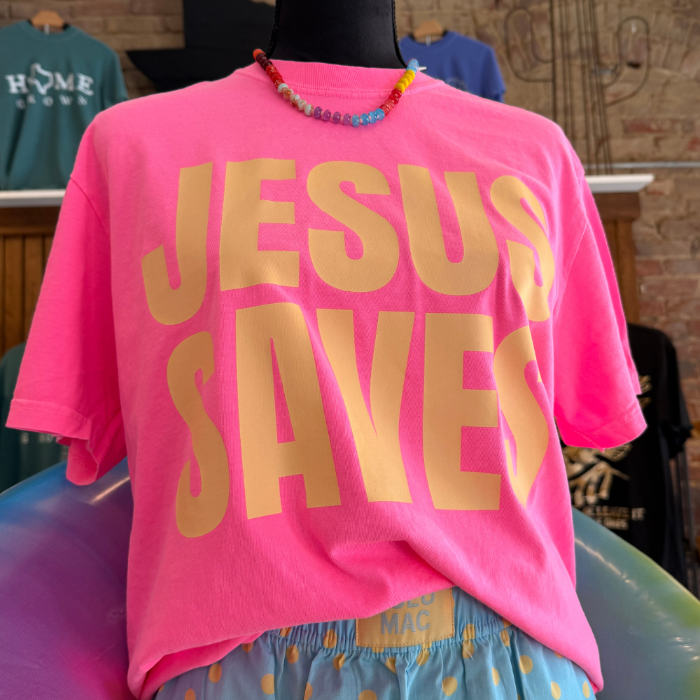 Jesus Saves neon pink Comfort Colors t-shirt displayed with colorful accessories.