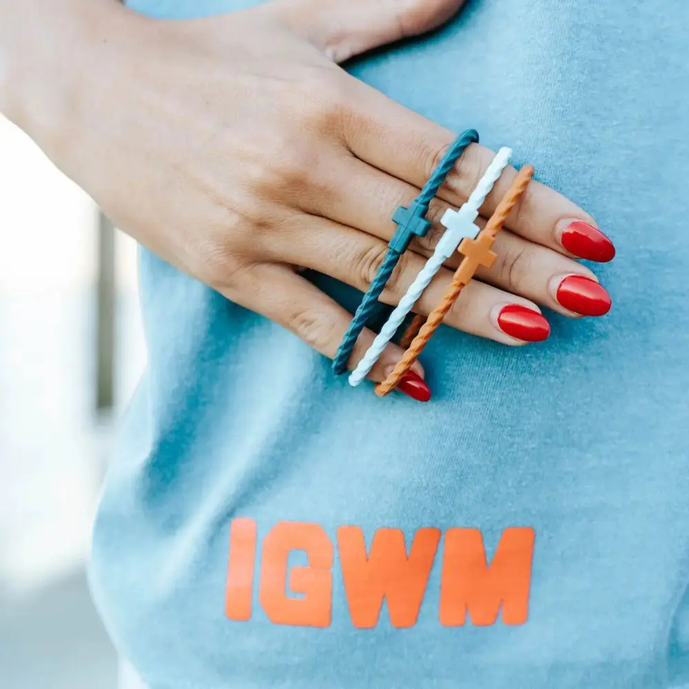 Close-up of Daybreak silicone cross bracelets in teal, white, and camel