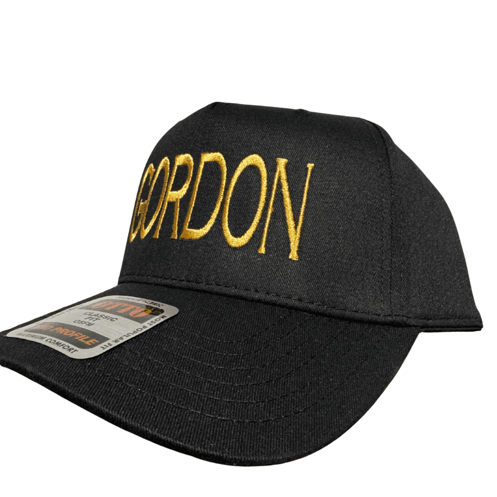 Side angle of black OTTO cap with gold GORDON embroidery