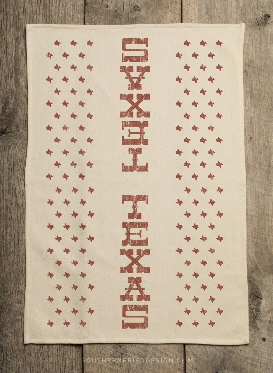 Full view of Texas kitchen towel with vertical TEXAS print and Texas-shaped stars