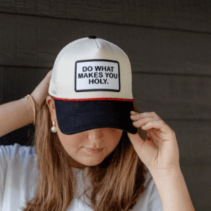 Woman wearing a cream and black snapback hat with embroidered patch that reads “Do What Makes You Holy”