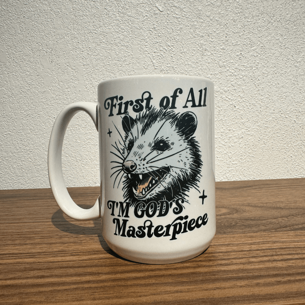 Ceramic mug with illustration of a possum and text that reads “First of All, I’m God’s Masterpiece”